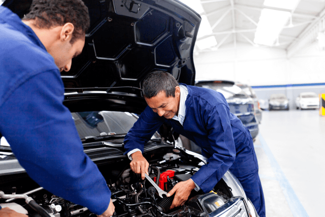 Two mechanics working together to fix the engine of a car